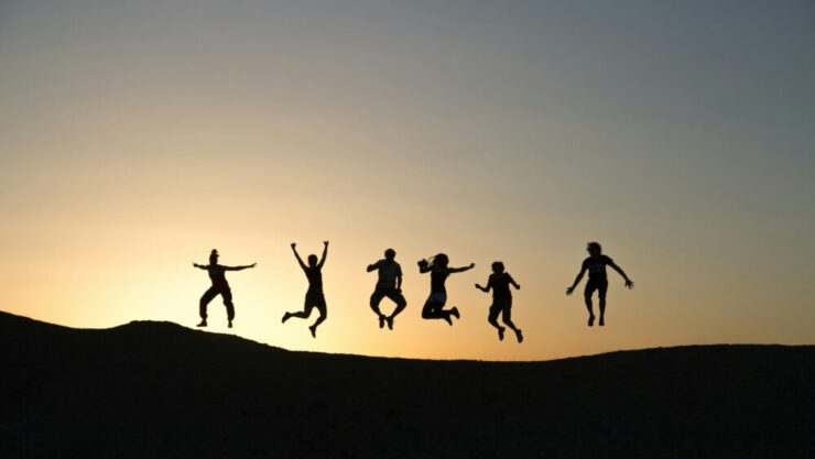 夕日の中で、6人がジャンプしている